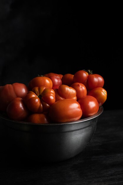 A bowl of tomatoes on a dark background