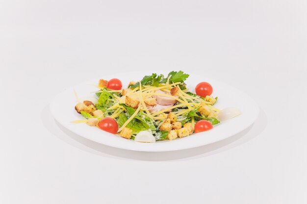 Ciotola di caesar salad tradizionale con pollo e pancetta isolato su sfondo bianco.