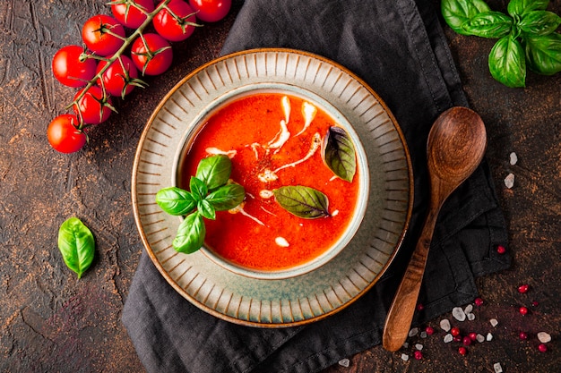 a bowl of traditional spain tomato soup with cream and basil on the dark background top view tomato