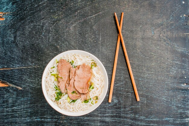 bowl of Traditional Vietnamese beef soup Pho Bo at the dark old wooden background