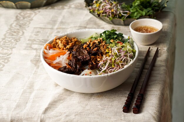 Bowl of traditional Vietnamese noodle salad - Bun Bo Nam Bo, with beef, rice noodles, fresh herbs, pickled vegetables and fish sauce