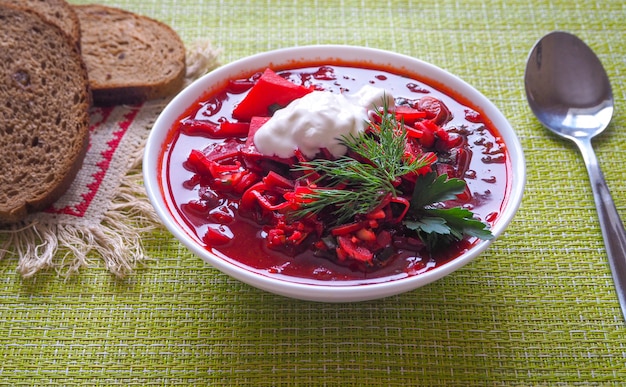Bowl of Ukrainian borscht on a white wooden table. Beet soup.