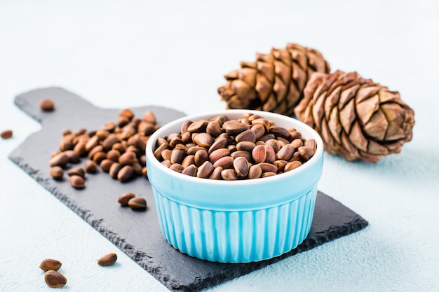 A bowl of unpeeled pine nuts and pine cones on a slate board. Detox and cure for insomnia. Healthy vitamin nutrition