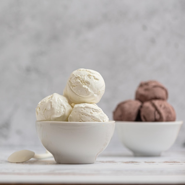 Photo bowl of vanilla and chocolate ice cream on light background side view