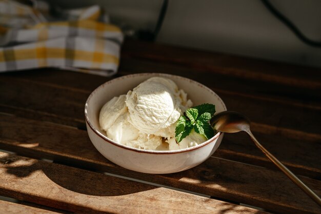 屋外の木製テーブルにバニラアイスクリームのボウル