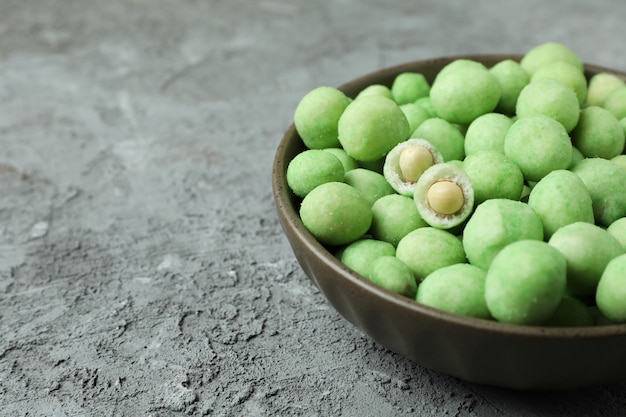 Bowl of wasabi nuts on gray textured