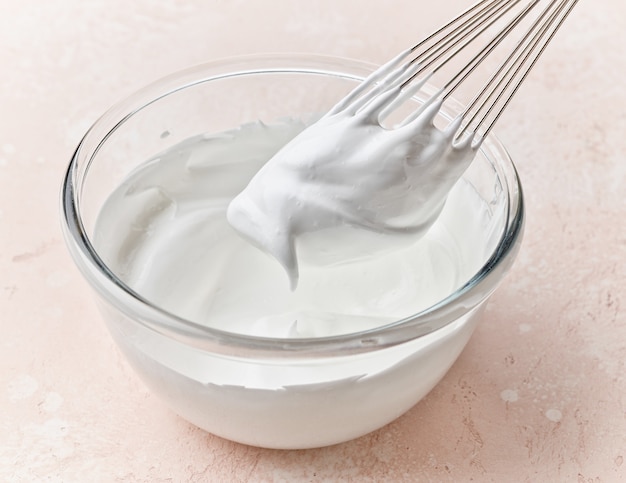 Bowl of whipped egg whites on pink kitchen table top