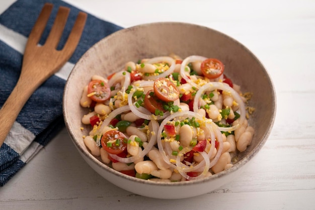 A bowl of white beans with tomatoes onions and onions