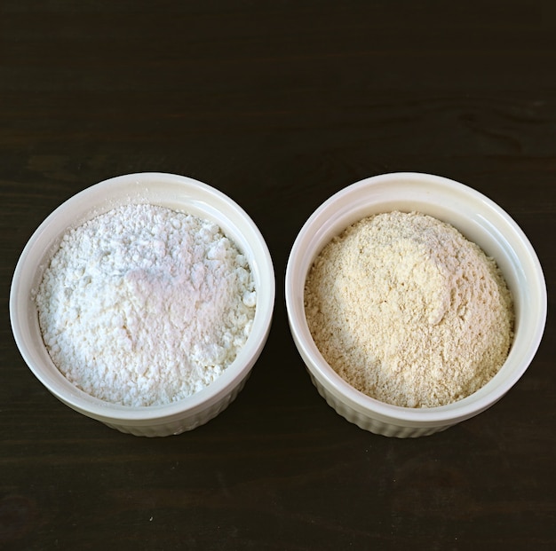 Bowl of White Flour and A Bowl of Whole-wheat Flour Isolated on Black Background