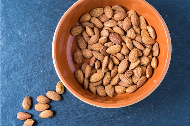 Una ciotola con noci mandorle su sfondo grigio.