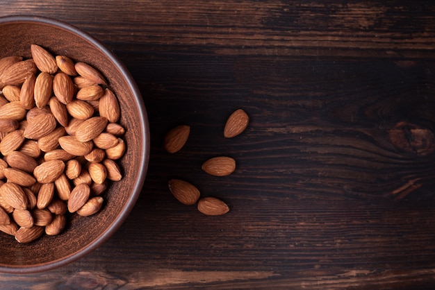 Bowl with almonds on wooden background