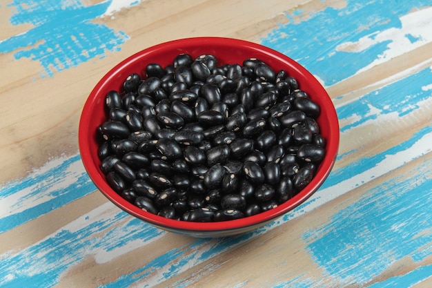 Bowl with black bean beans on blue rustic wooden table top view