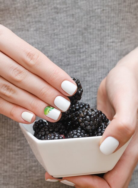 Bowl with blackberries in female hands.