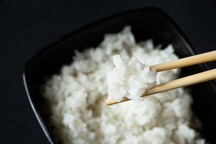 Photo 黒の背景に白ご飯を茹でたボウル。アジア料理と竹箸。