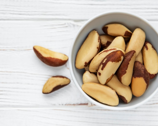 Bowl with Brazil nuts on wooden table