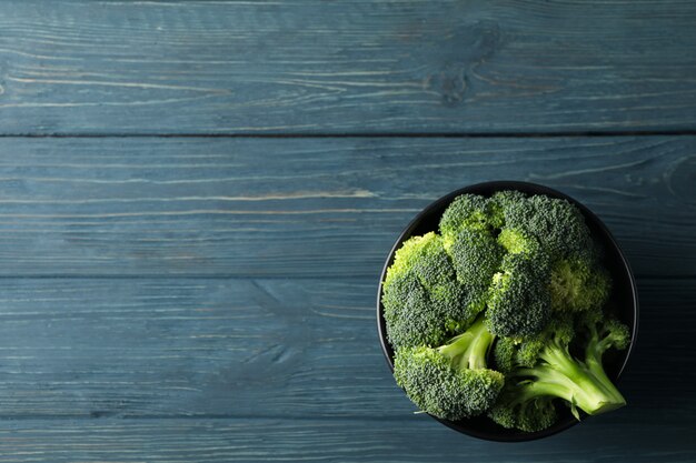 Bowl with broccoli on wooden, top view. Healthy food