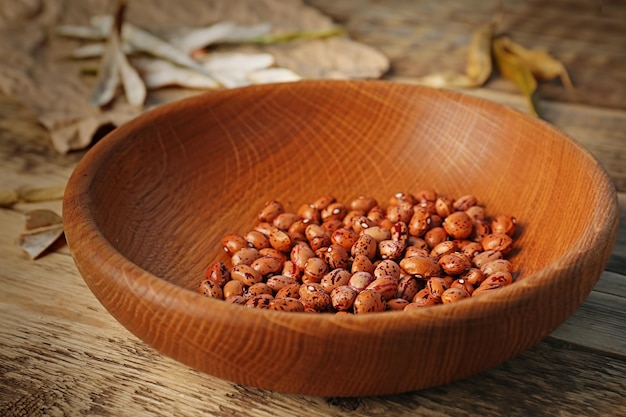 Bowl with brown haricot beans on wooden table