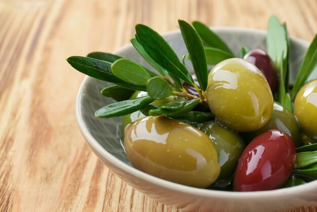 Bowl with canned olives on wooden background