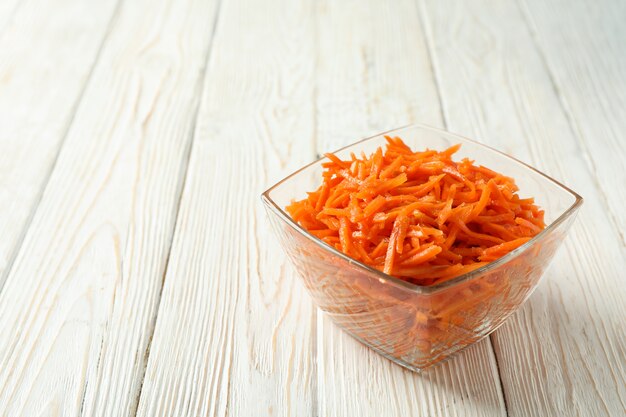 Bowl with carrot salad on wooden background