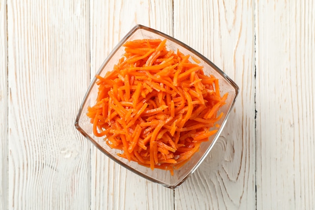 Bowl with carrot salad on wooden background