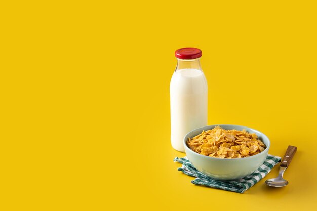 Bowl with cereals and milk bottle for breakfast on yellow background