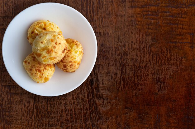 Bowl with cheese bread on wooden table