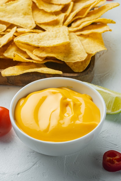 Foto ciotola con salsa di formaggio con nachos, sul tavolo bianco