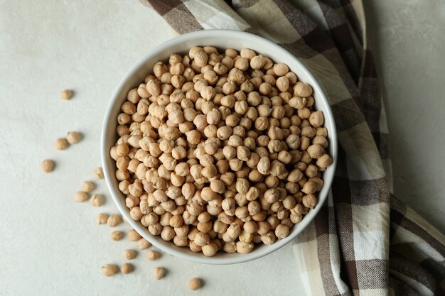 Bowl with chickpea on white textured table with kitchen towel