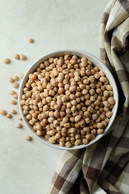 Bowl with chickpea on white textured table with kitchen towel