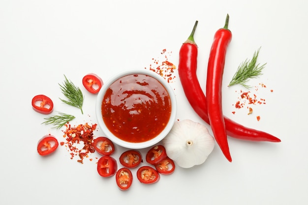 Bowl with chilli sauce, pepper and garlic on white