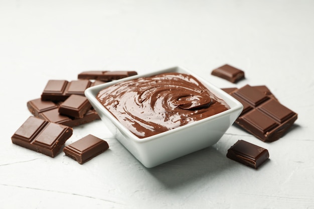 Bowl with chocolate and chocolate pieces on white