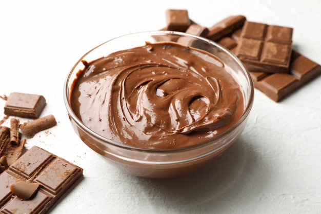 Bowl with chocolate and chocolate pieces on white