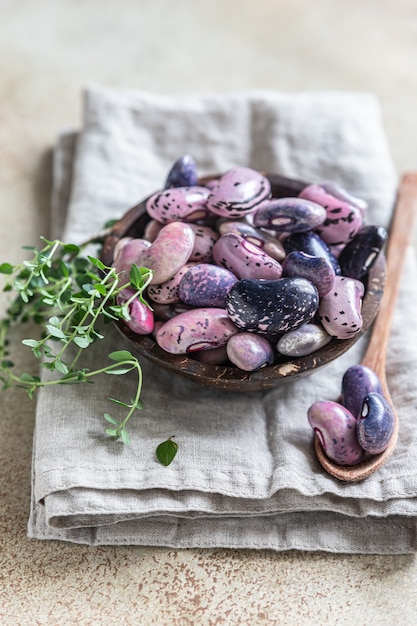 Bowl with colorful legumes and thyme, concrete background. Vegan high protein product.