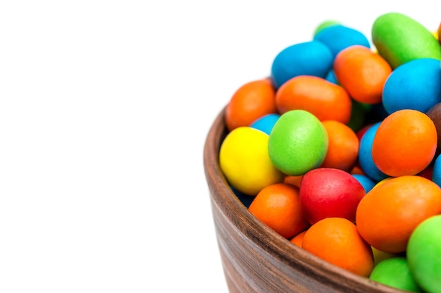 Bowl with colorful round candies isolated on white Close up