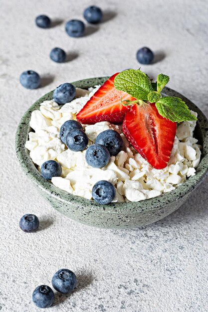 Una ciotola con ricotta yogurt frutti di bosco mirtilli fragole e menta fresca su un gr