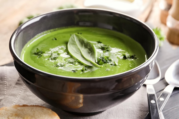 Bowl with delicious spinach soup on table