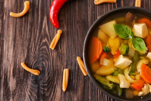 Bowl with delicious turkey soup on wooden background