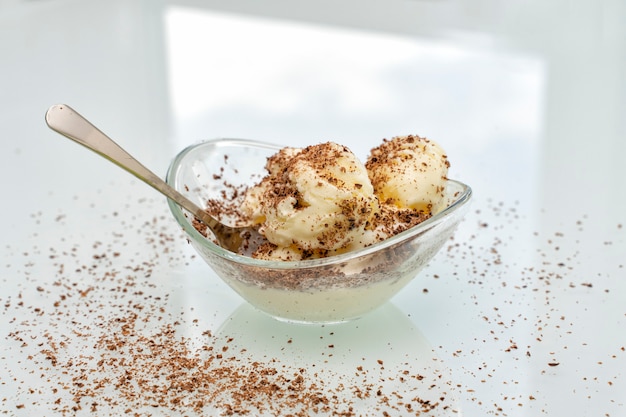 Bowl with delicious vanilla ice cream sprinkled with chocolate chips with a spoon on the table