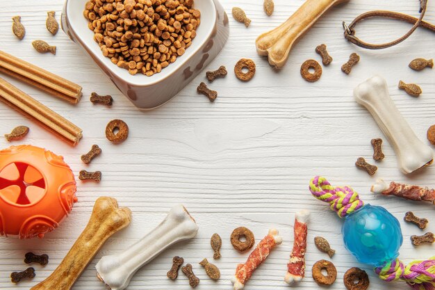 A bowl with dog food dog treats and toys on a wooden floor
