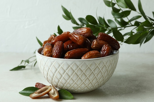 Bowl with dried dates on white textured table