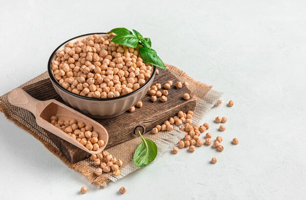 A bowl with dry raw chickpeas on a gray background side view space for copying