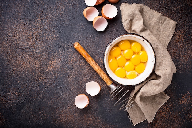 Bowl with eggs yolks and whisk