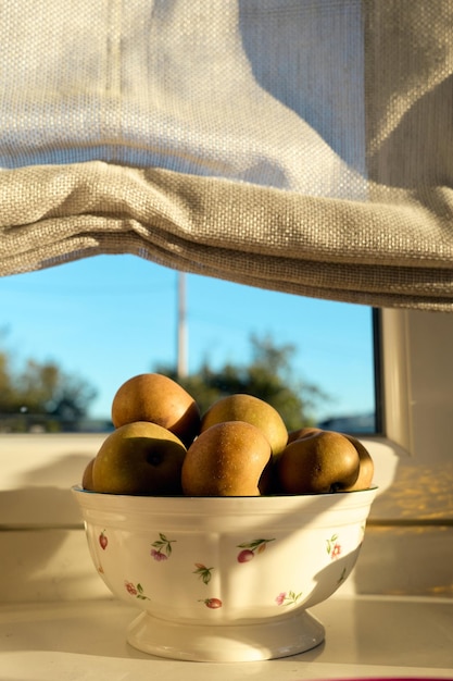 Bowl with a few apples near a window