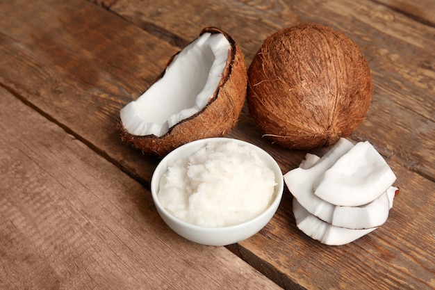 Bowl with fresh coconut oil and nut on wooden table