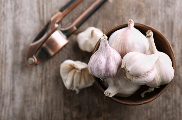 Bowl with fresh garlic on wooden table