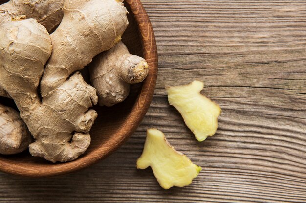 Bowl with fresh ginger on wooden table