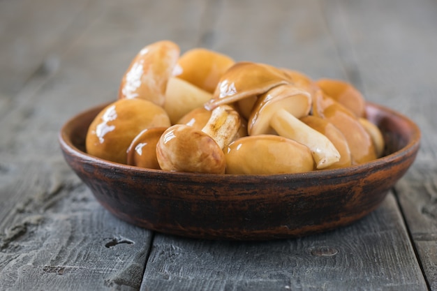 Bowl with fresh mushrooms from the forest on the village table. Natural vegetarian cuisine.