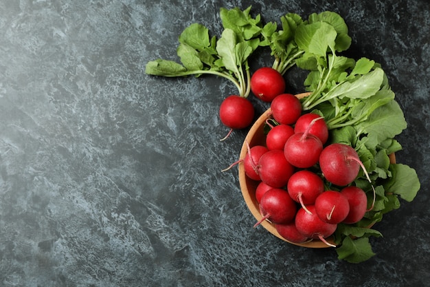 Bowl with fresh radish on black smokey table