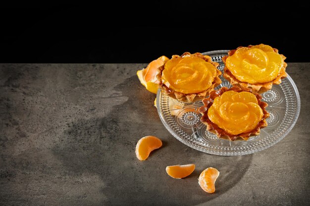 Bowl with fresh tangerines on dark metal table close up