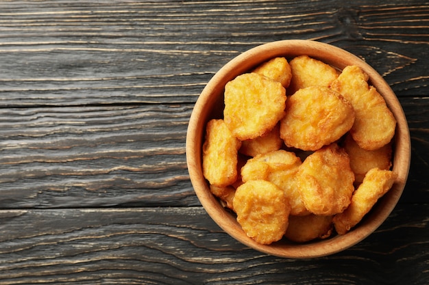 Foto ciotola con pepite di pollo fritto su fondo in legno